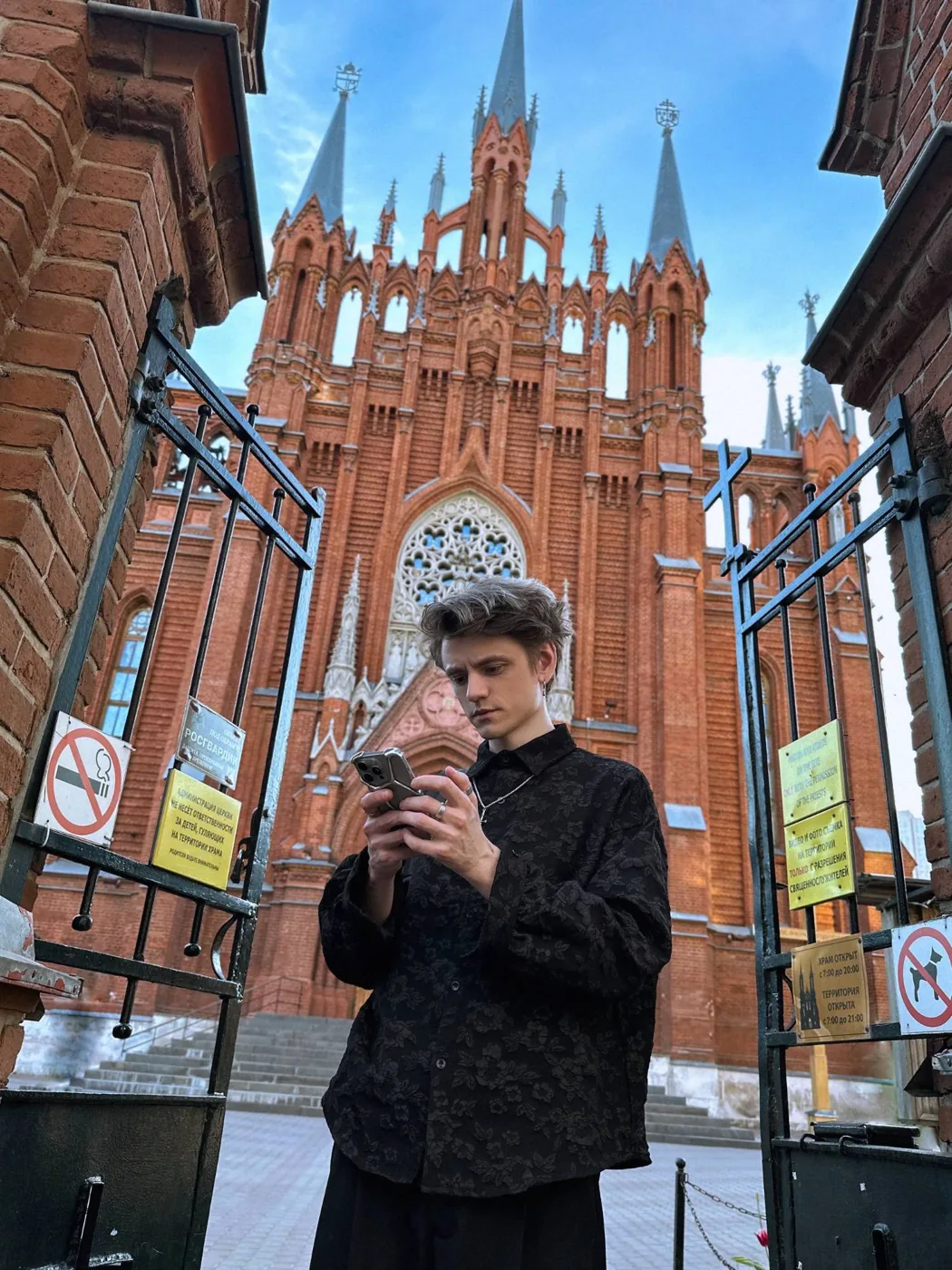 С телефоном у ворот краснокирпичного собора